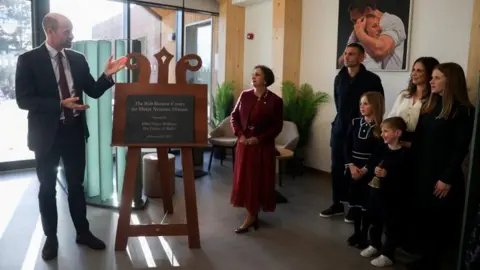 Temilade Adelaja/PA Wire The Prince of Wales speaks during the unveiling of a plaque in front of Dr Agam Jung, Lindsay Burrow and their children Missy, Maya, Jackson and Kevin Seinfeld