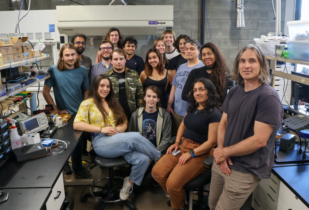 A group of 15 researchers smile at the camera.
