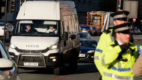 PA Media A white Iveco truck stood on the road with uniformed police officers in front