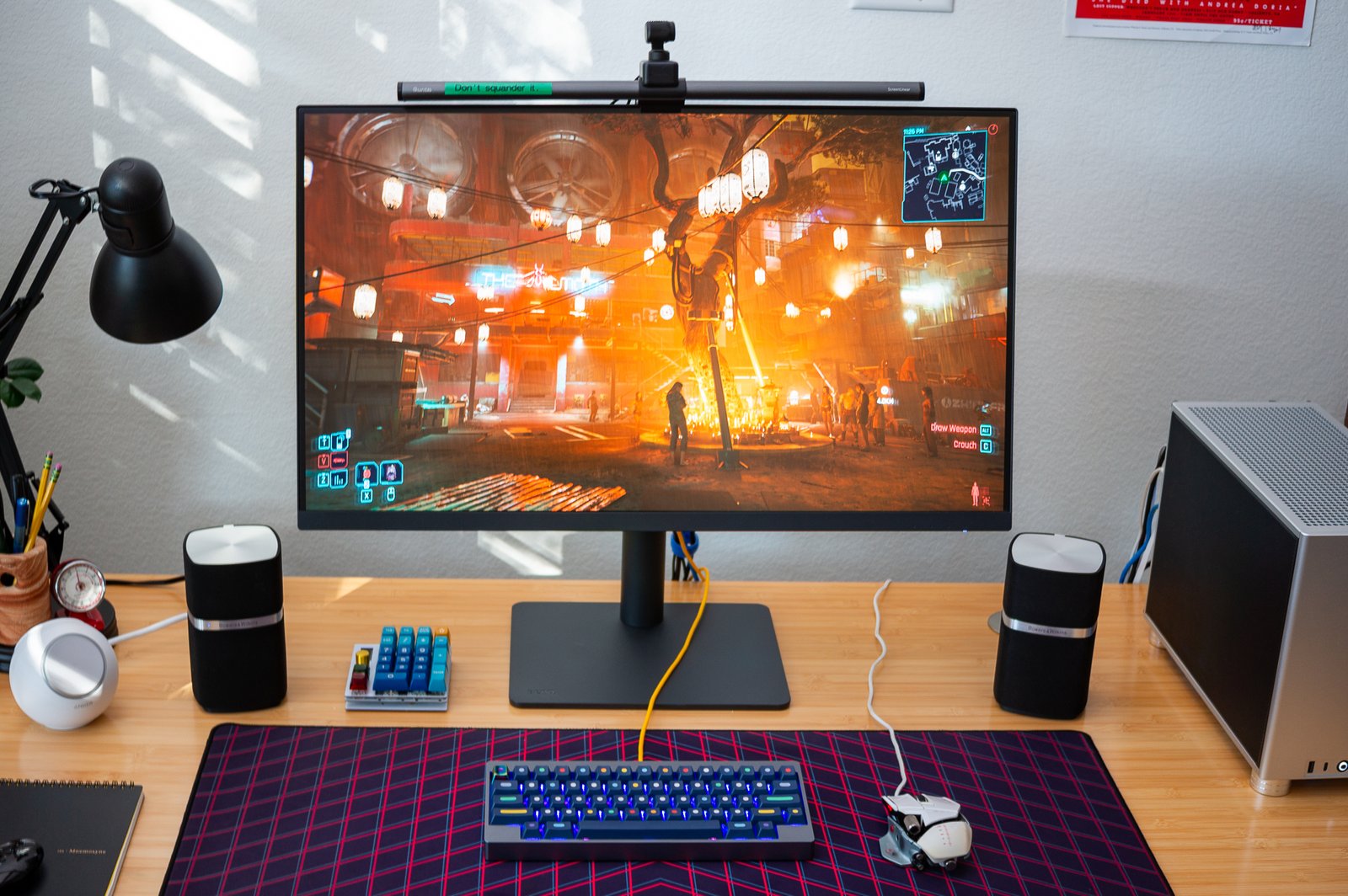 a 32-inch monitor on a wooden desk, displaying a night scene from cyberpunk 2077.