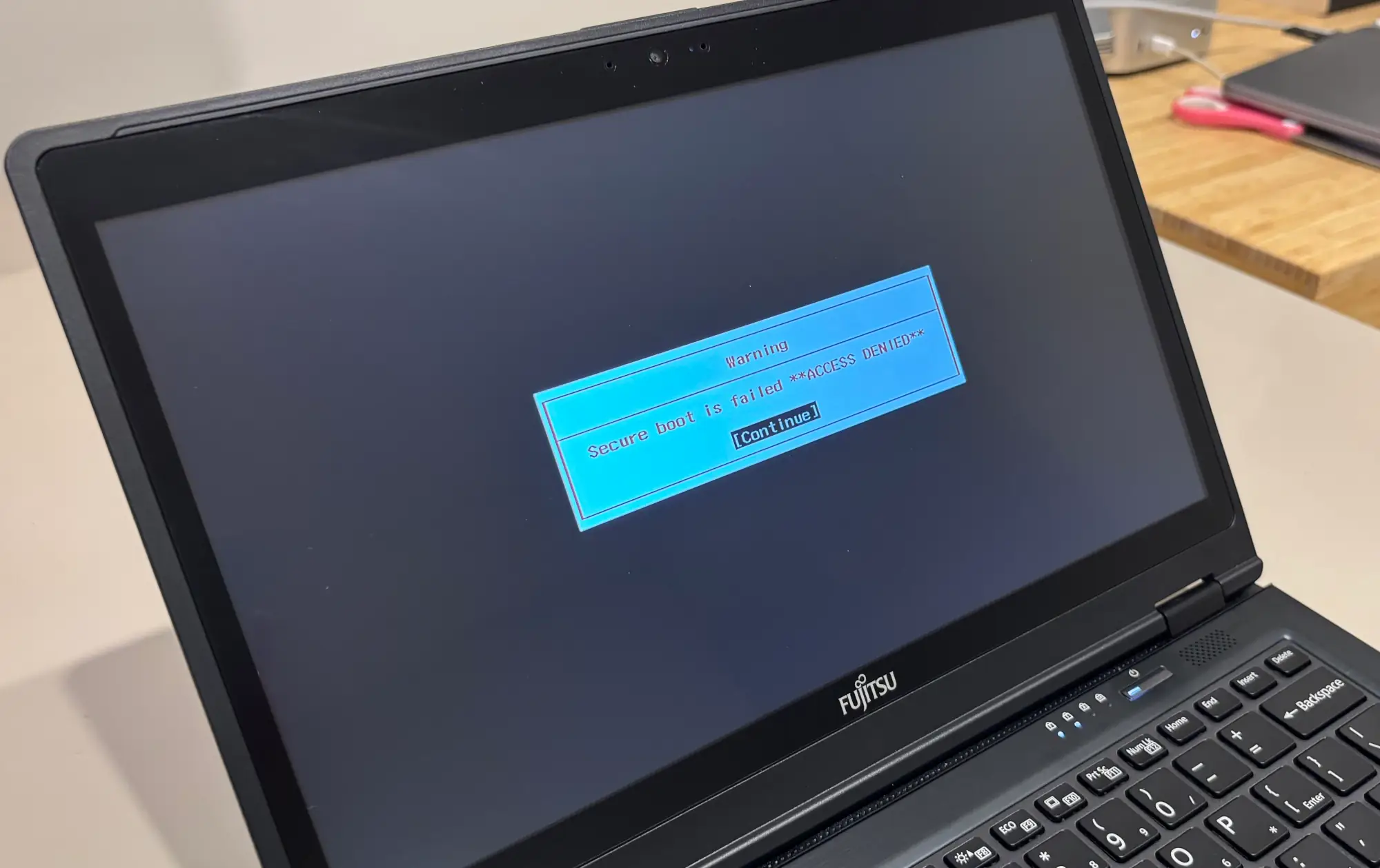 A photograph of the laptop screen showing an error message, red text on white: 