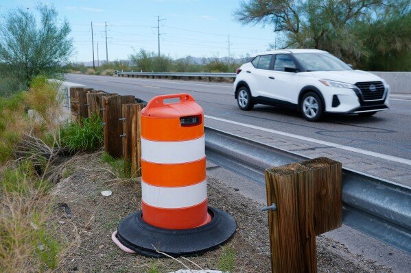 A license plate reader used by U.S. Border Patrol is hidden in a traffic cone while capturing passing vehicles on AZ Highway 85, Tuesday, Oct. 21, 2025, in Gila Bend, Ariz. (AP Photo/Ross D. Franklin)