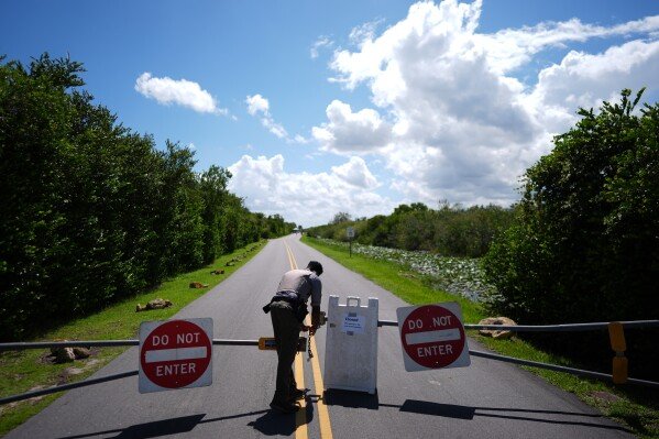 National Park Service law enforcement ranger Greg Freeman opens a locked gate closing vehicle access to the Shark Valley section of Florida