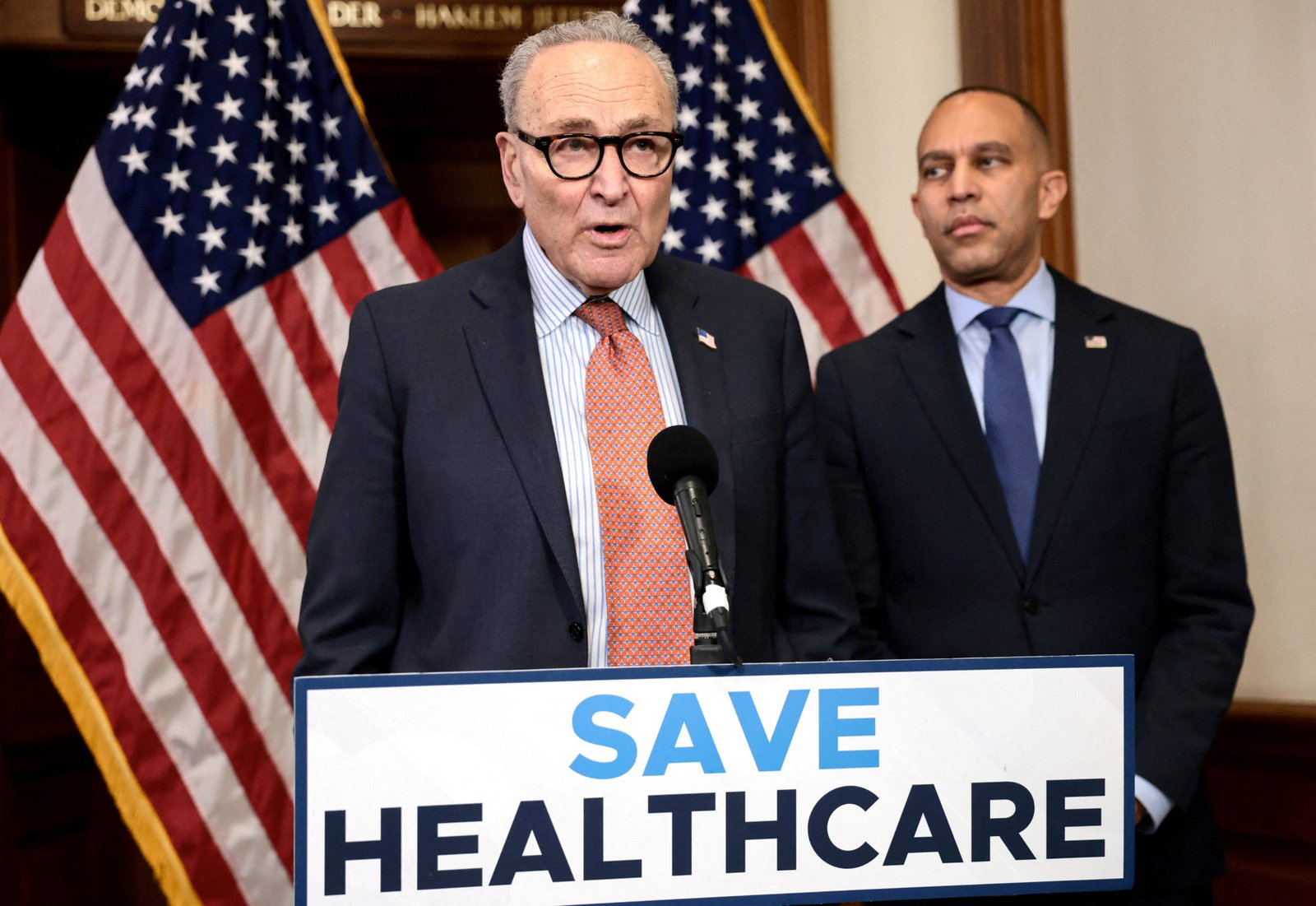 Senate Minority Leader Chuck Schumer, D-N.Y., and House Minority Leader Hakeem Jeffries, D-N.Y., stand at a podium with a sign that says, 