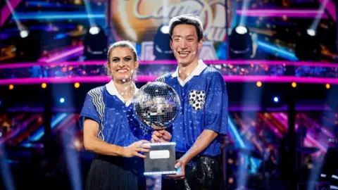 Karen Carney and Carlos Go with their trophy after winning the 2025 series of Strictly Come Dancing.