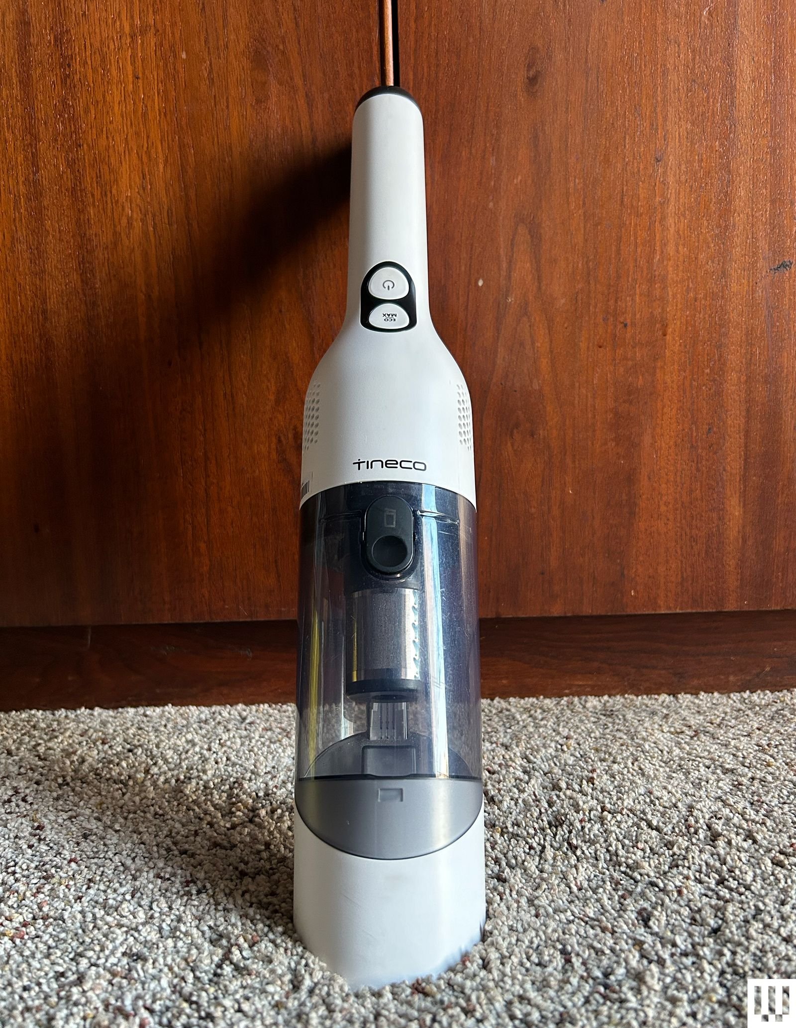 The Tineco Go Mini Cordless Handheld Vacuum is resting on a wooden board and a rug