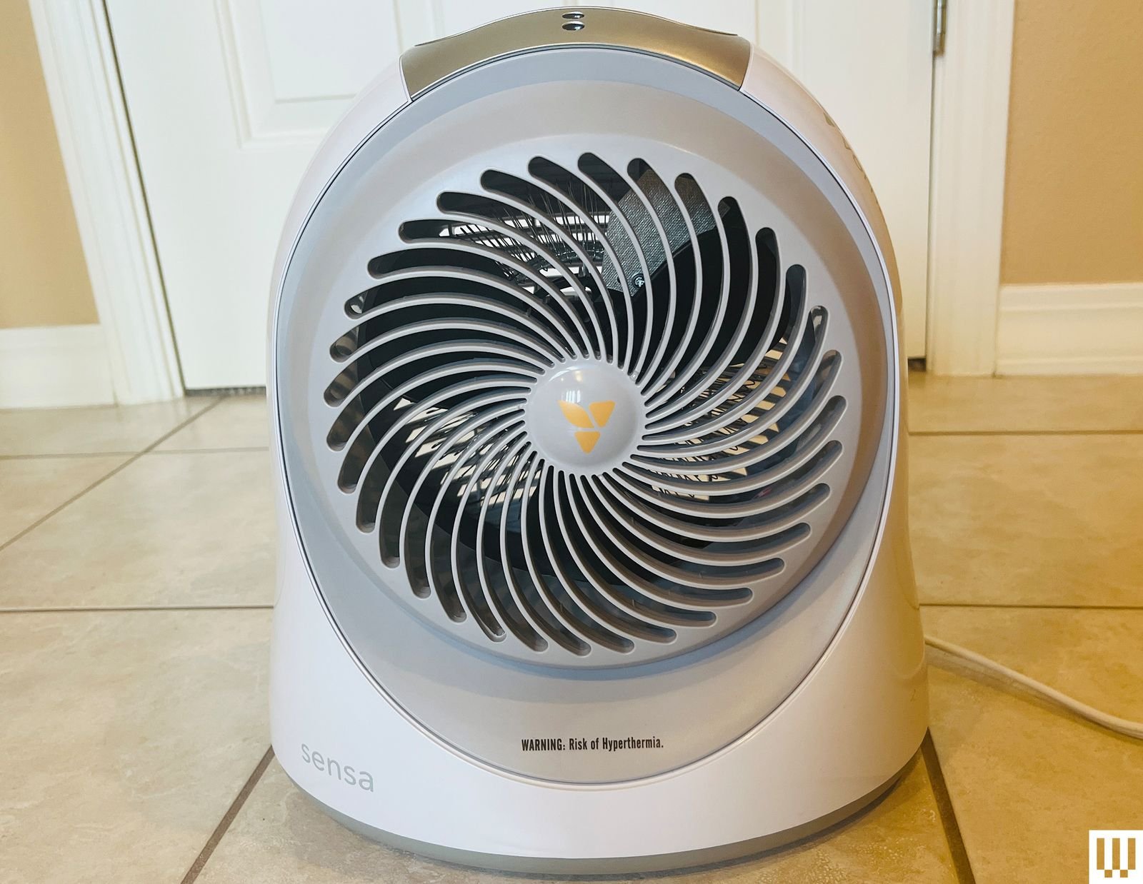 Front view of the Vornado Sensa Cribside Heater a small ovalshaped fan sitting on a tile floor.