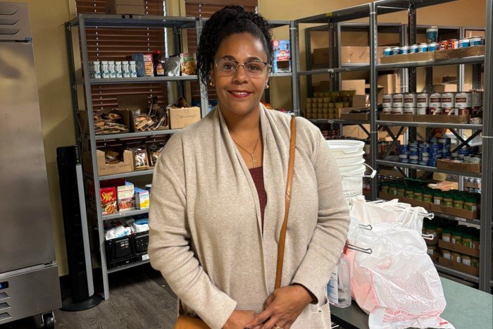 Briana Martin stands in front of pantry shelves stocked with food at Covenant House.