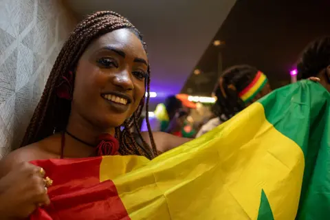 NurPhoto via Getty Images Close-up of a woman holding the Senegalese flag.