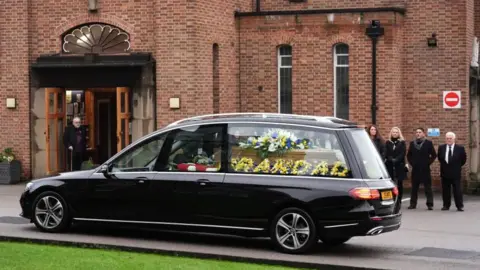 PA Media Floral tributes in and around the coffin carried in the hearse, including one that says 