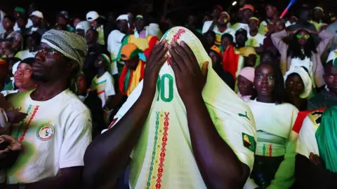 Reuters: A Senegalese fan covers his face with a football shirt printed with the number 10.