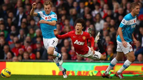 Richard Heathcote/Getty Images Footballer Ji Sung Park wearing a red shirt appears to fly as he falls after a challenge between Sunderland and Manchester United.
