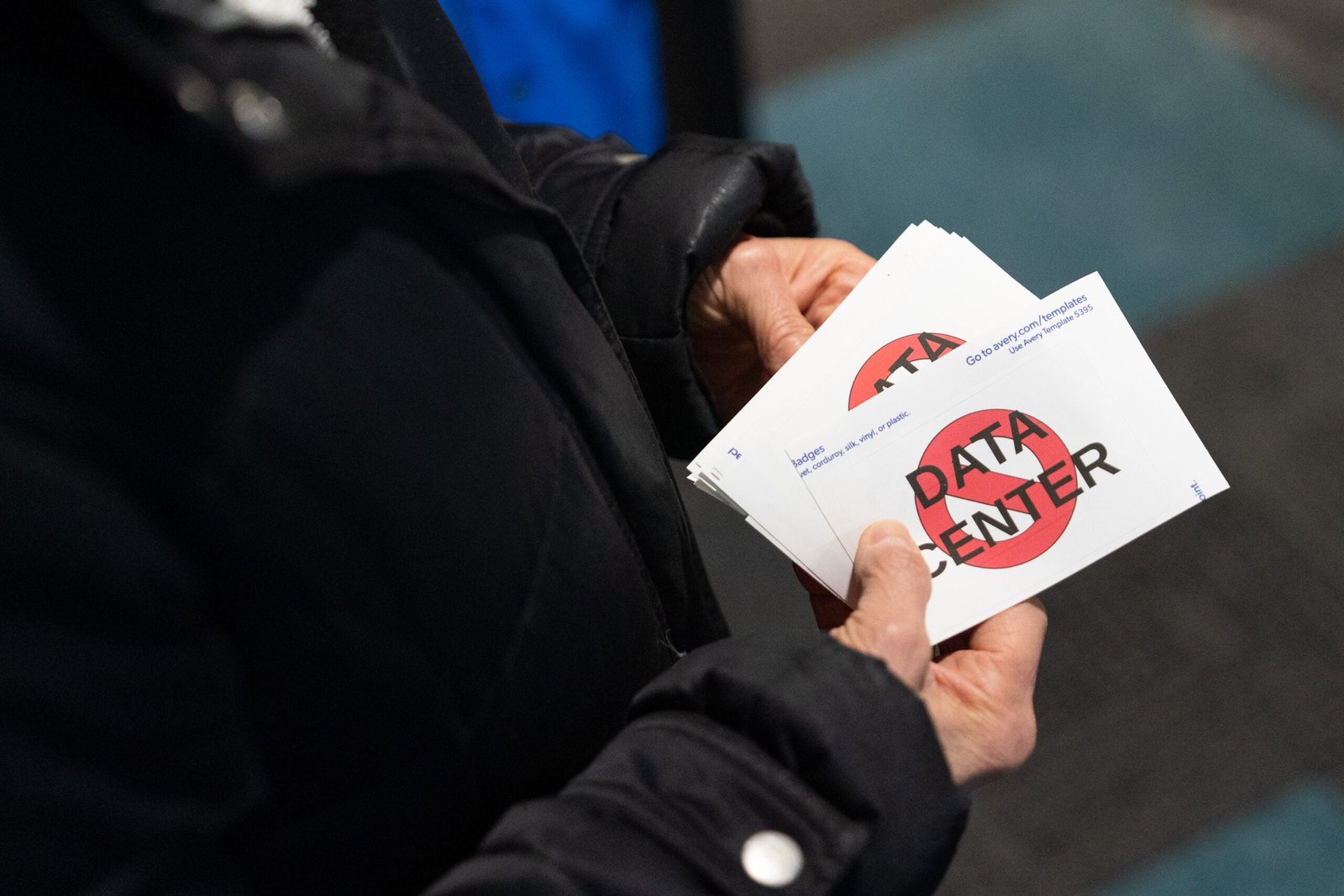 A person holds a stack of stickers with the words DATA CENTER crossed out by a red prohibition symbol.
