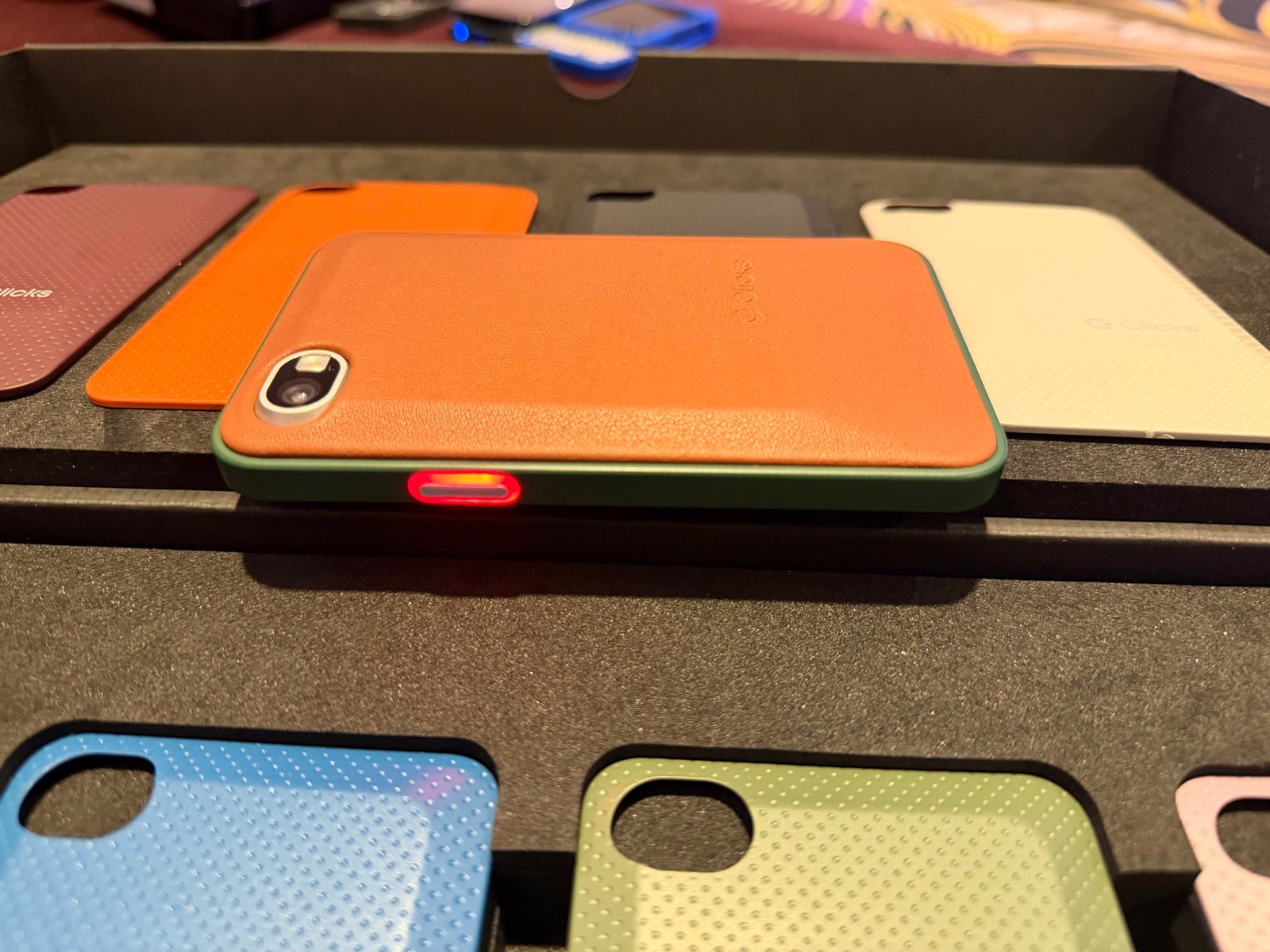 Image showing the Clicks Communicator device, with an orange casing and a red-lit notification button on the side.