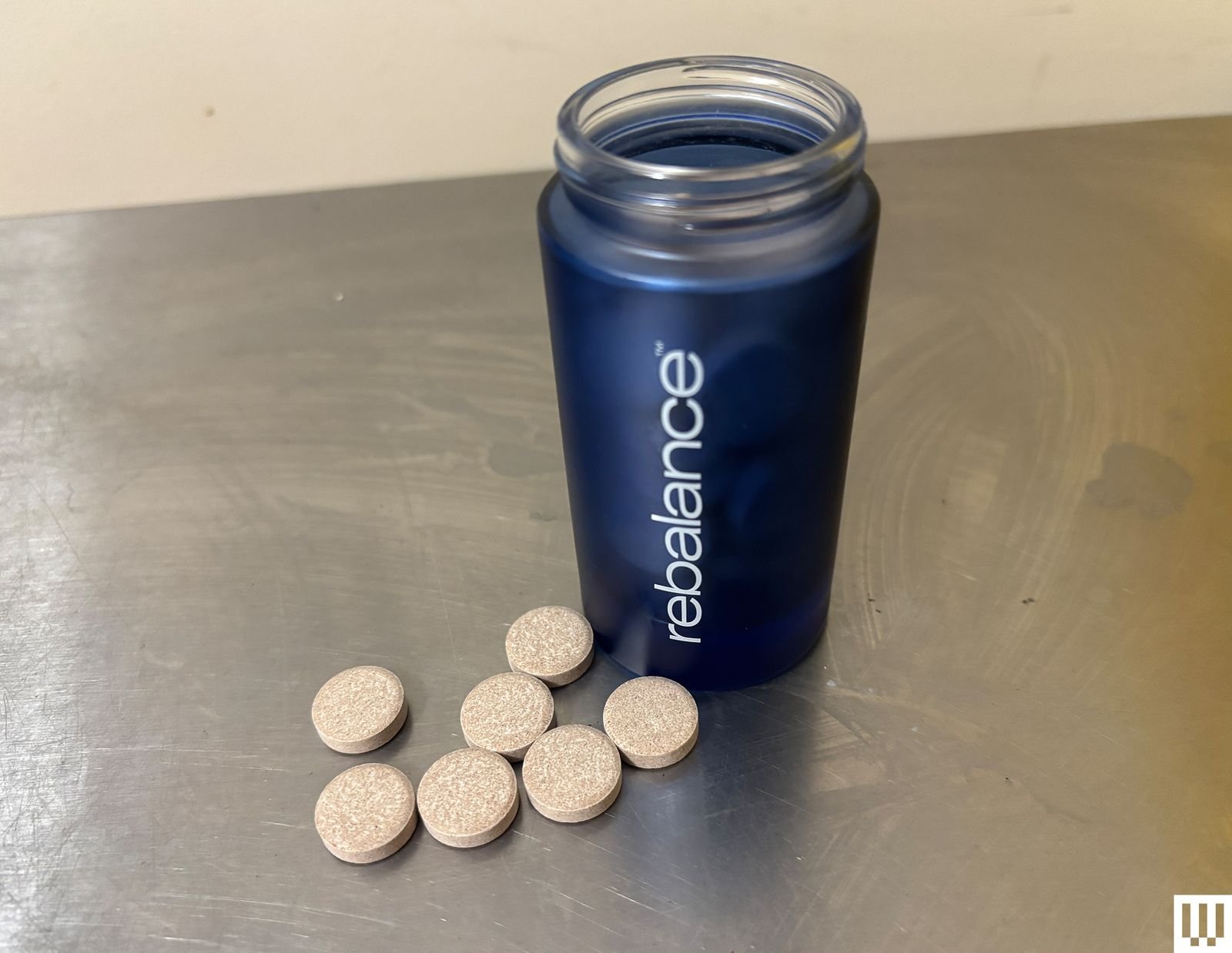 A jar with a blue label next to round tablets on the table
