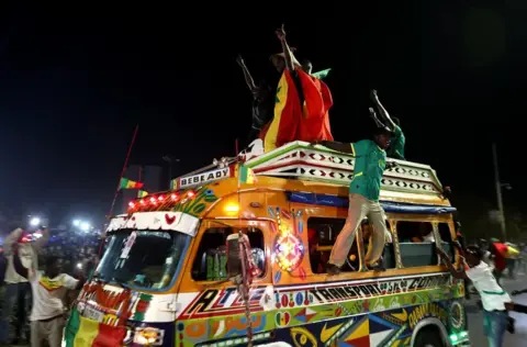 Reuters Fans lean out the windows of a minibus in celebration.