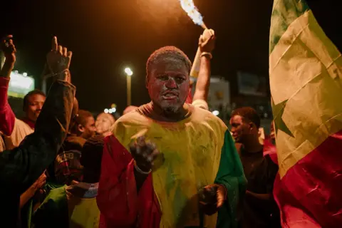 AFP via Getty Images A Senegalese fan celebrates in the fan zone at the African Renaissance Monument in Dakar