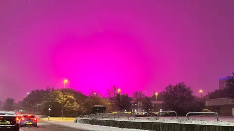 Bright pink skies over a snowy Birmingham road
