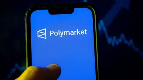 LightRocket via Getty Images In this photo illustration, a Polymarket logo is seen displayed on a smartphone. 
