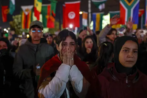 ANP via Getty Images A Moroccan fan puts her hands in front of her face. Other fans around look sad.