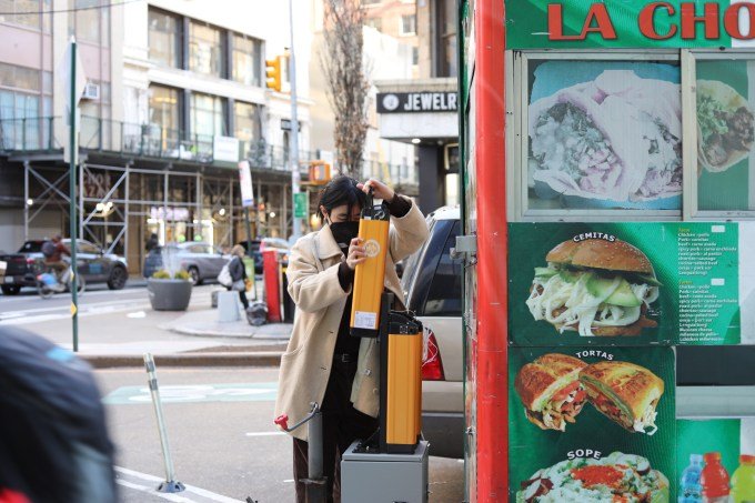 A woman replaces a battery in a food truck on a city street.