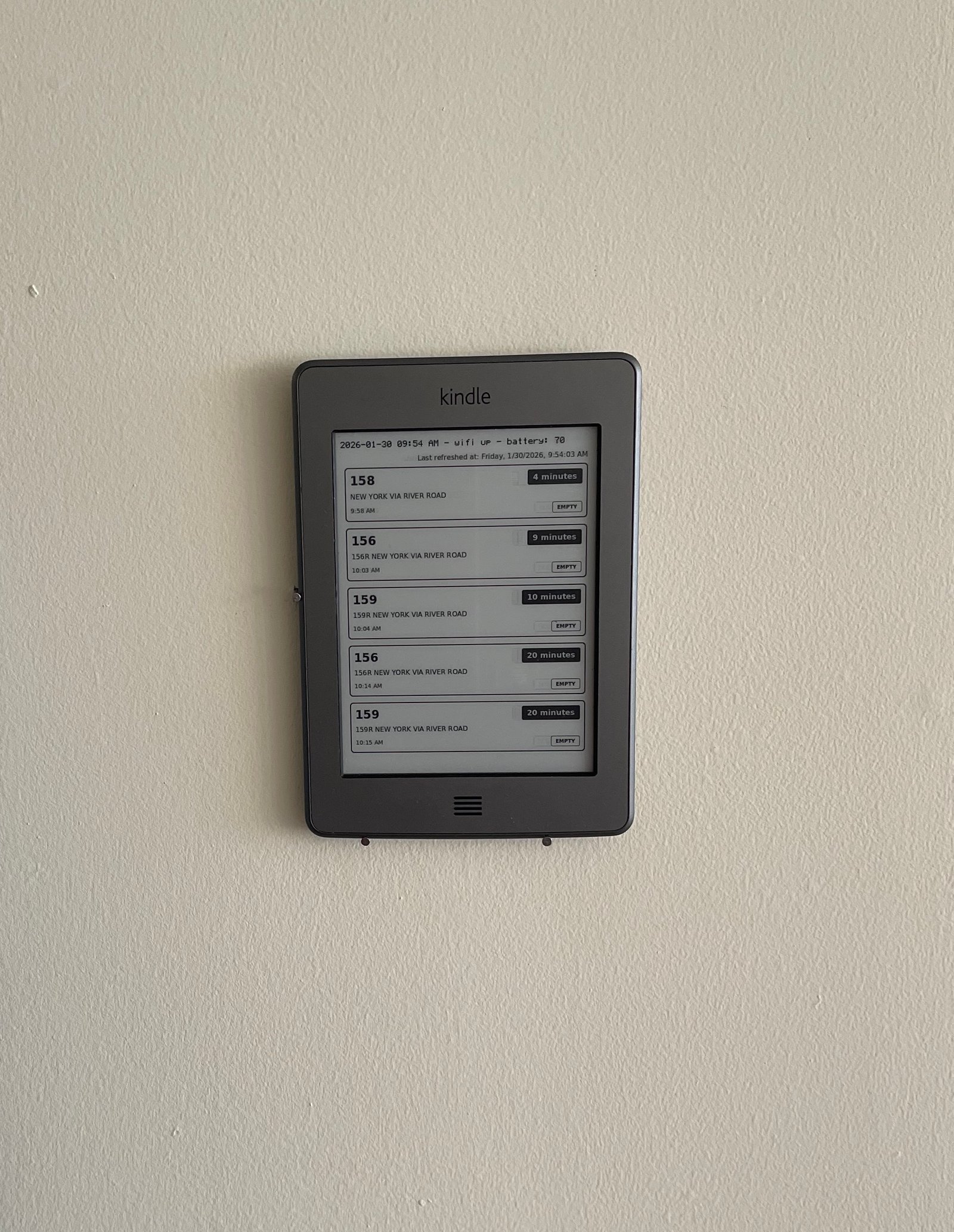 Kindle mounted to a wall displaying bus arrival times