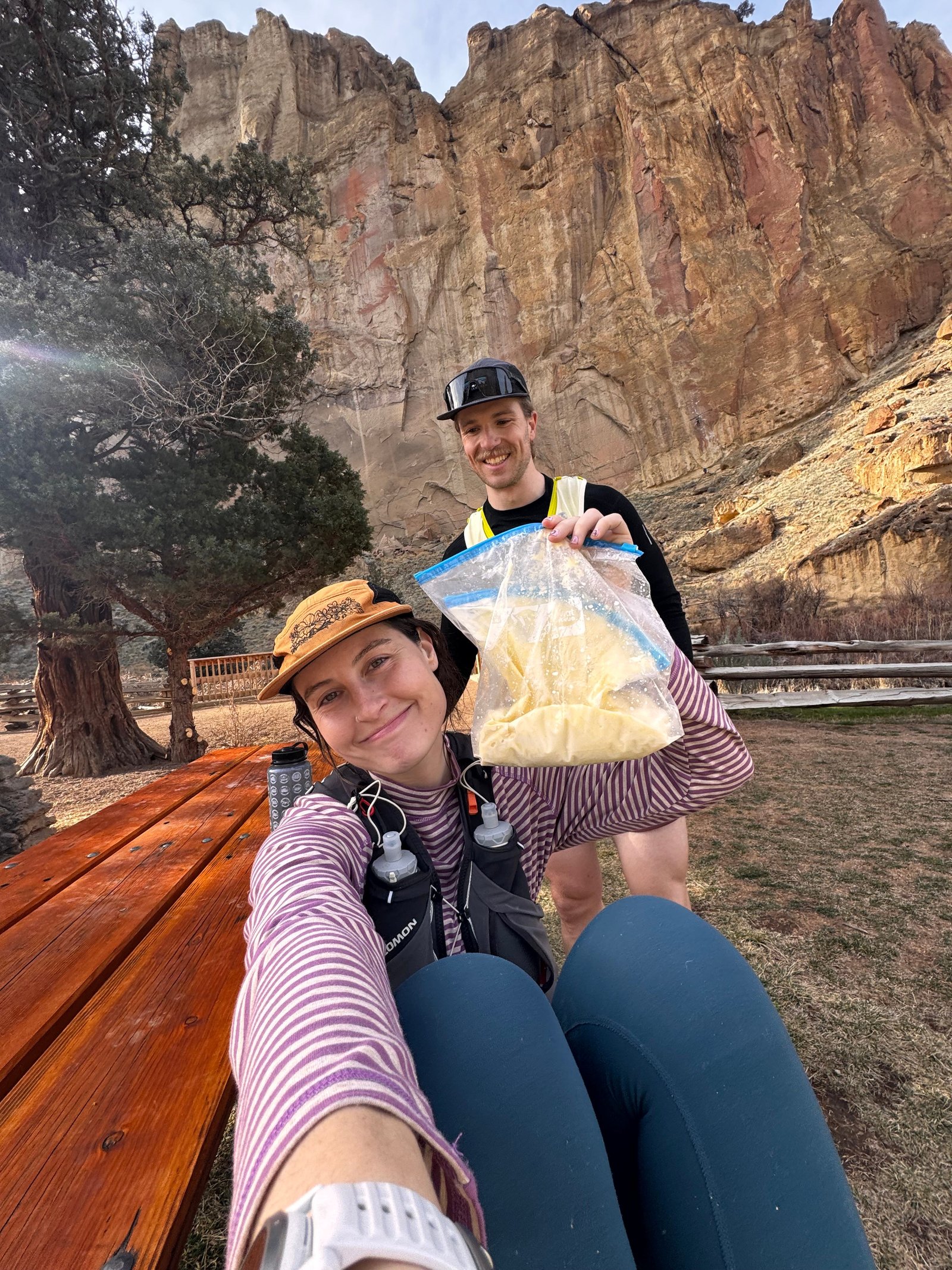 Hikers relaxing on a bench with mountainous background.