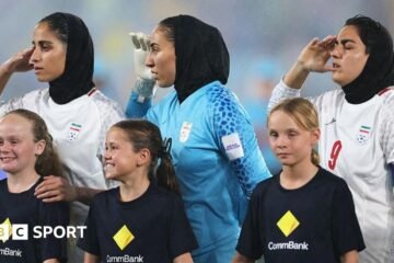 Iranian footballers sing and salute the national anthem at the Asian Cup after a prior silence
