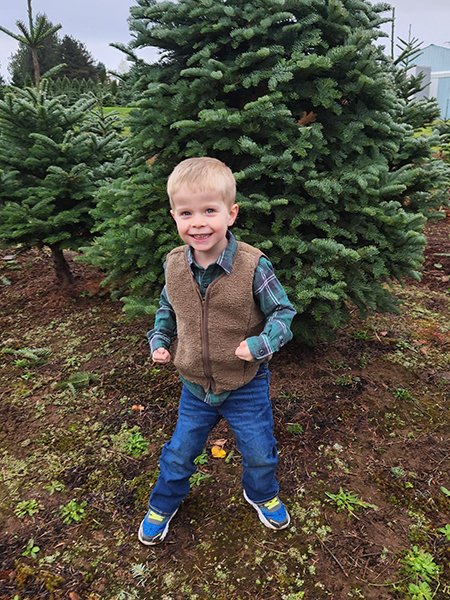 Boy stands in front of tree outdoors