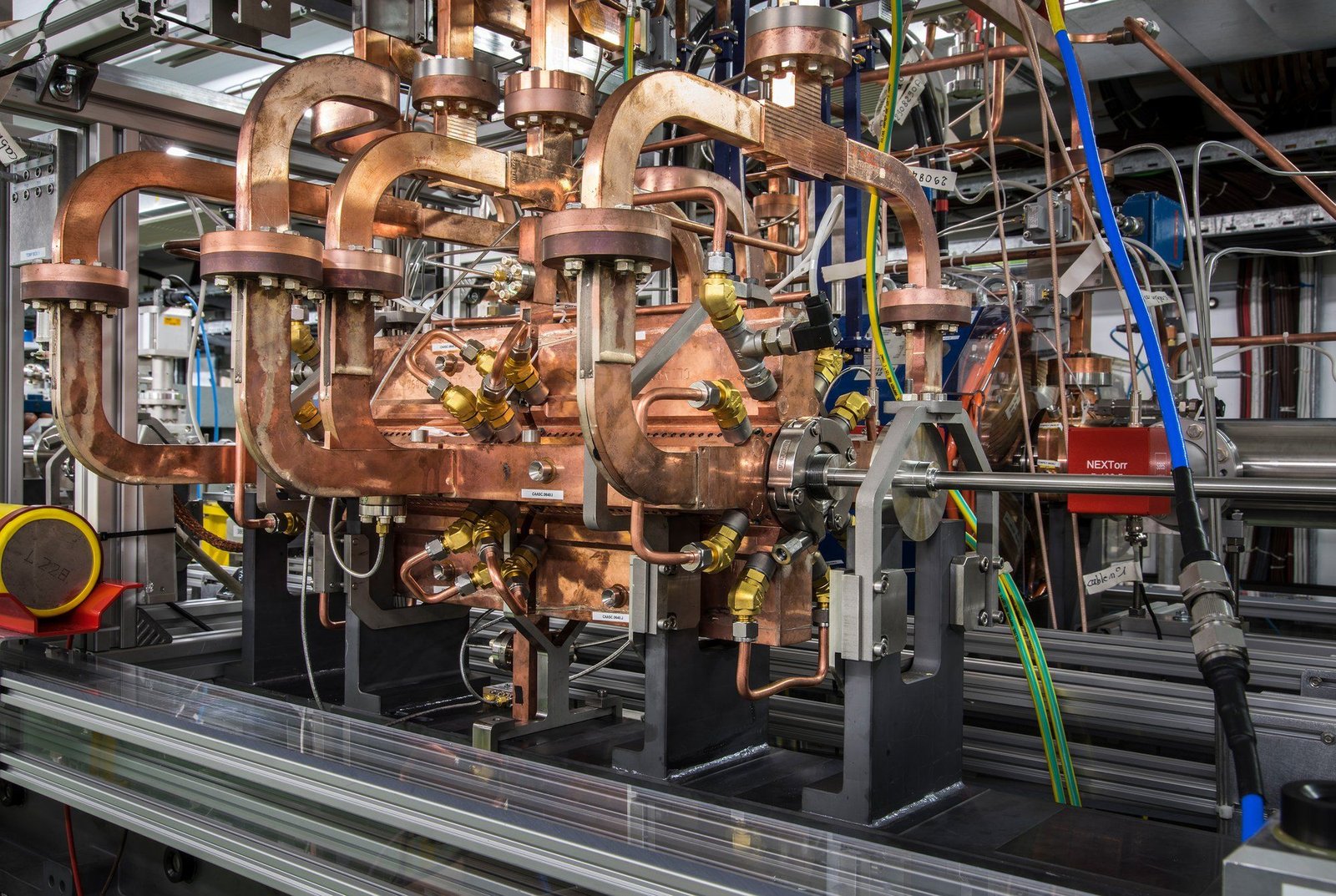 Photo of floor-to-ceiling electromagnetic hardware with many tubes and pipes, some of which is copper-colored.