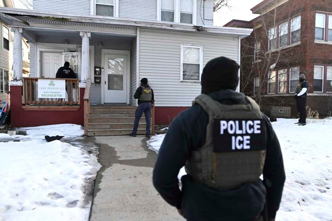ICE agents approach a house before detaining two people in Minneapolis on Jan. 13.