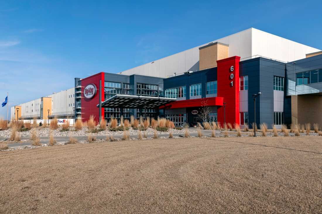 This photo shows the outside of DigiKey’s 2.2 million square-foot warehouse. The building has a long rectangular shape and has red accents near an entrance area.